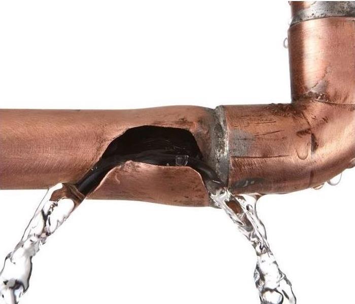 Water leaking from tear in pipe